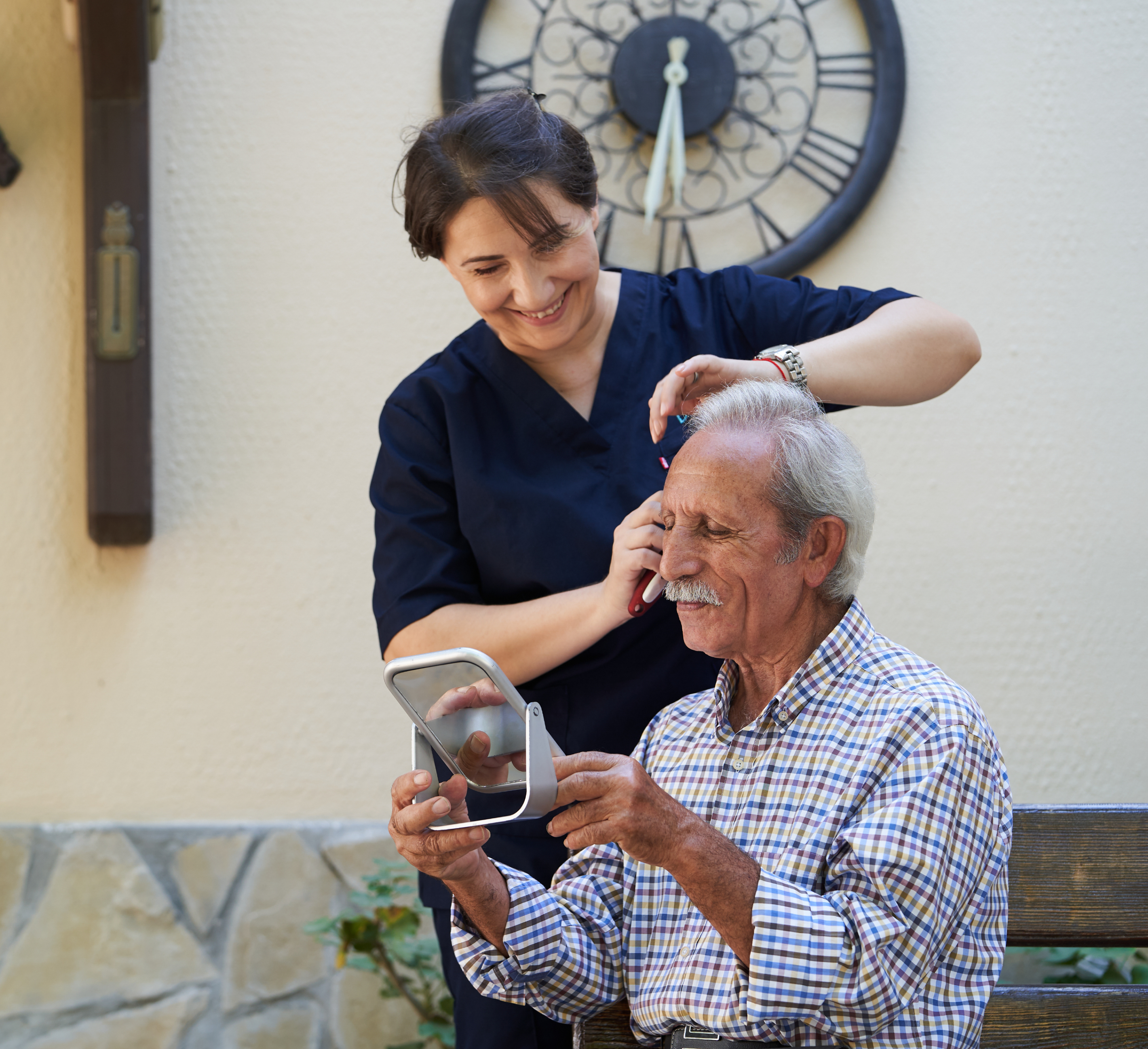 A professional carer helping a gentleman with his haircut outdoors