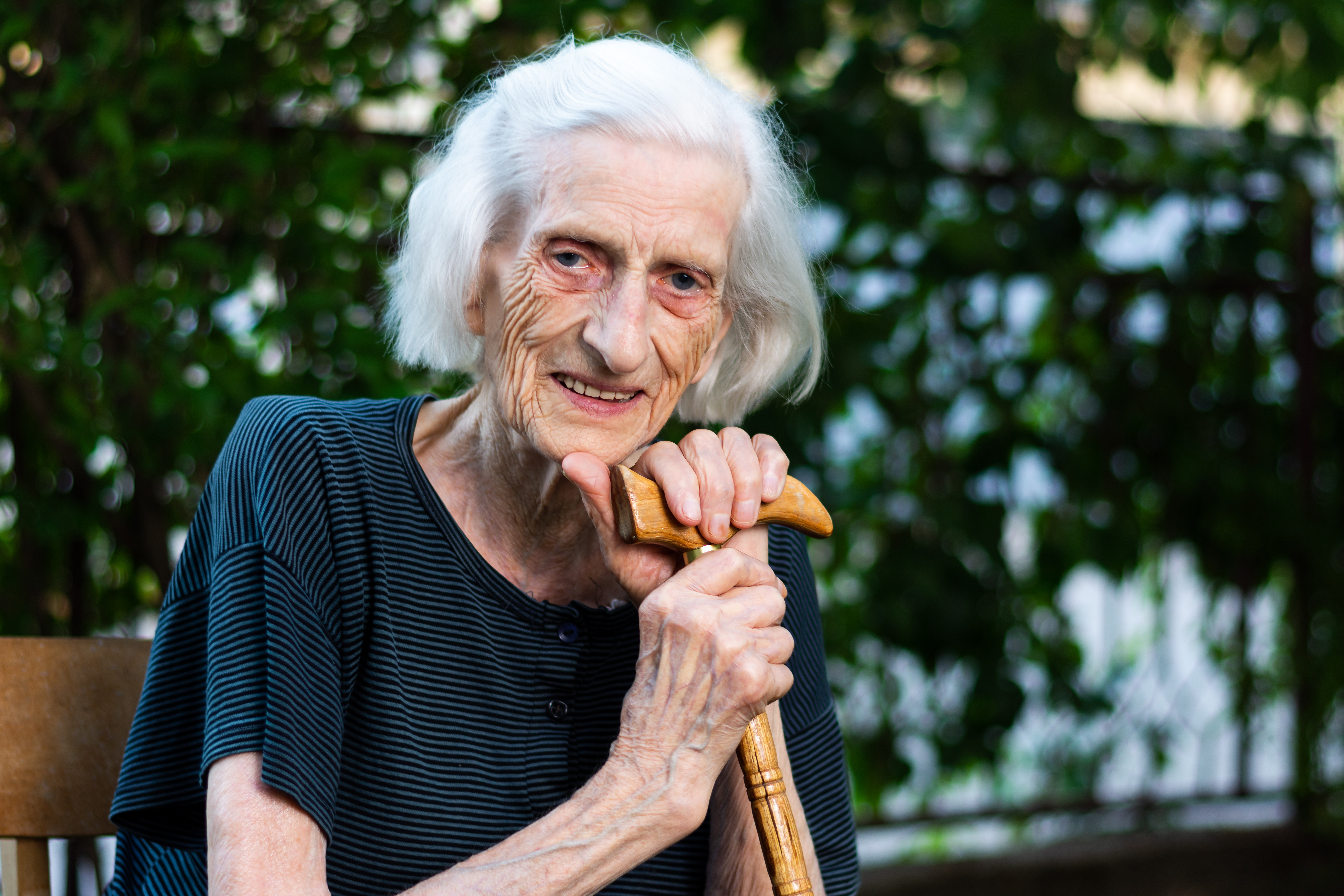 A woman with a walking stick relaxing in her garden