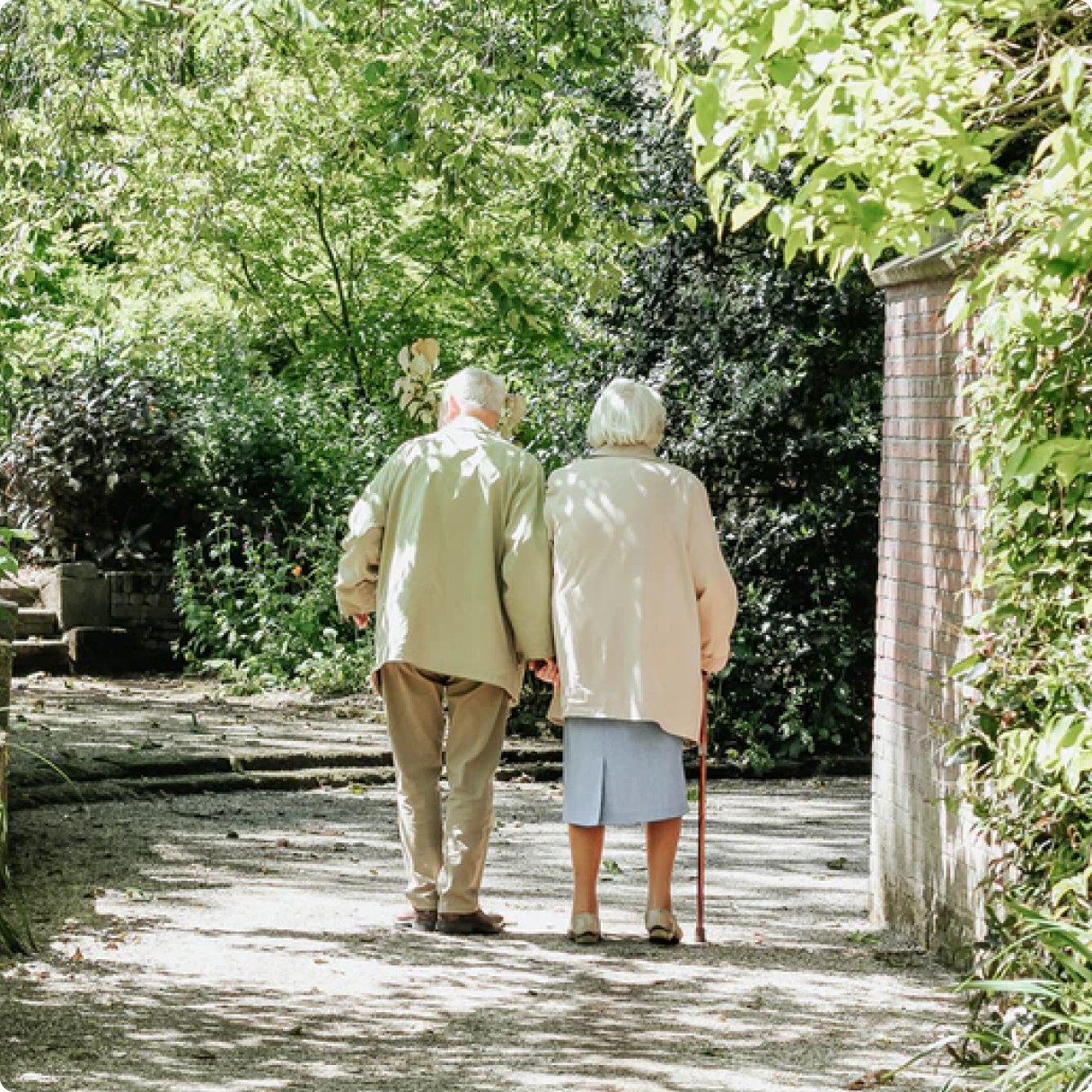 An older couple walking together in a leafy garden