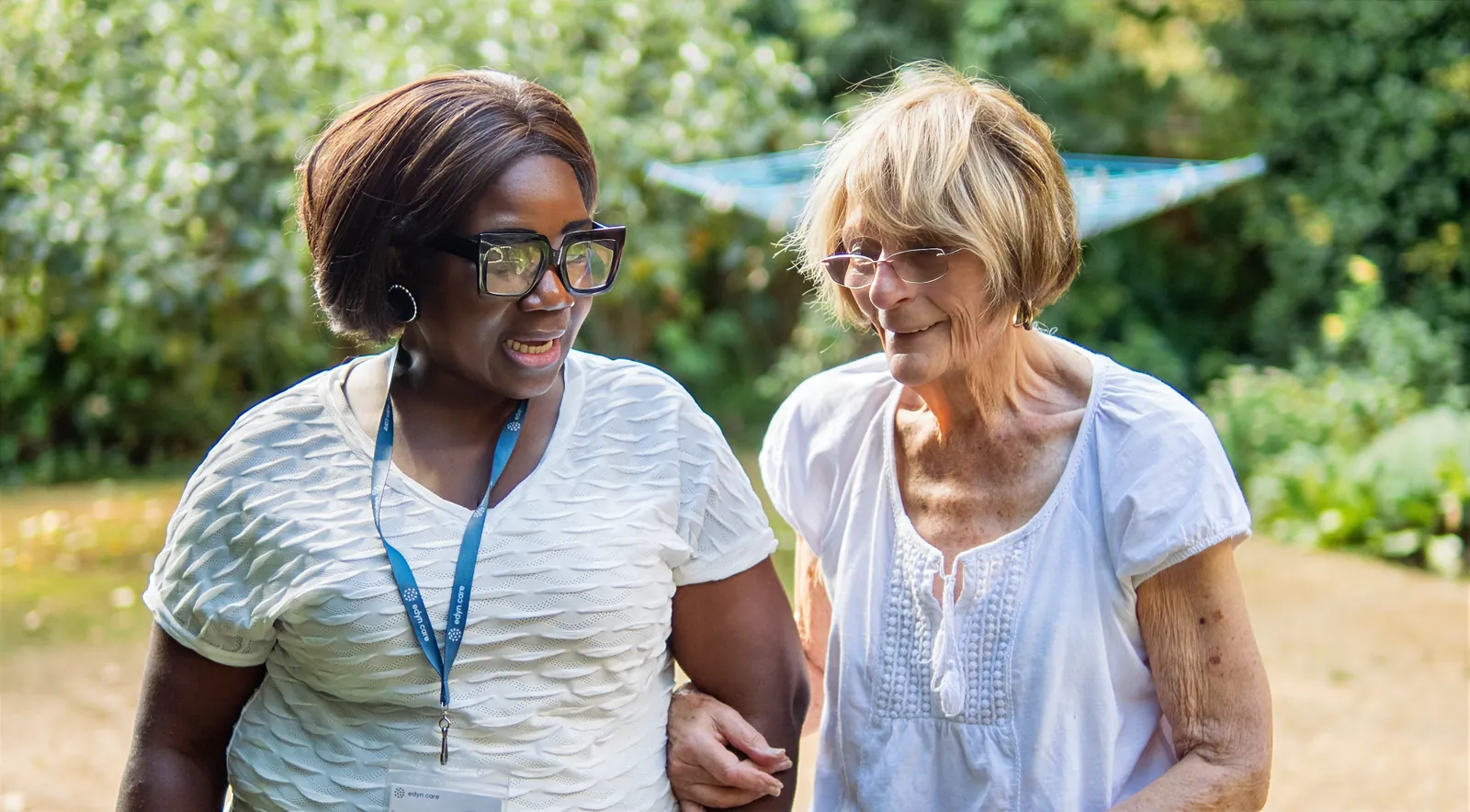 An Edyn carer walking with an older woman in her garden